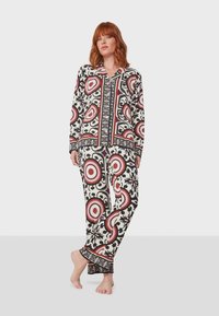 Conjunto de pijama de manga larga con un patrón floral en blanco y negro con acentos rojos, diseñado con una camisa de botones y pantalones ajustados.