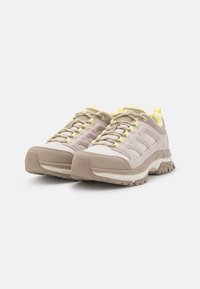 Beige hiking shoes with textured fabric, yellow accents, and a rugged sole. Features reinforced toe and mesh panels for breathability.