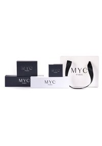 Quattro scatole in bianco e nero con il logo "MYC PARIS". Presentano una maniglia nera, forme e dimensioni diverse, su uno sfondo bianco.