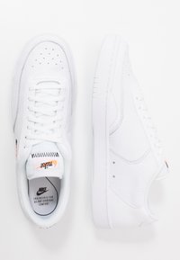 Adidași din piele albă cu un superior texturat, vârf rotund și detalii perforate. Caracteristici: sistem de închidere cu șireturi răsucite și accente de branding minime.