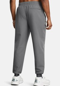 Graue Sporthose mit elastischem Bund, seitlichen Reißverschlusstaschen und schmal zulaufenden Bündchen. Hergestellt aus leichtem, glattem Stoff. Strukturierte Passform.