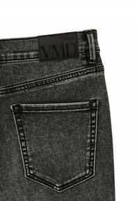 Jean en denim noir avec une texture, comprenant une poche arrière et une patch en cuir portant l'inscription "VMD" au niveau de la taille.
