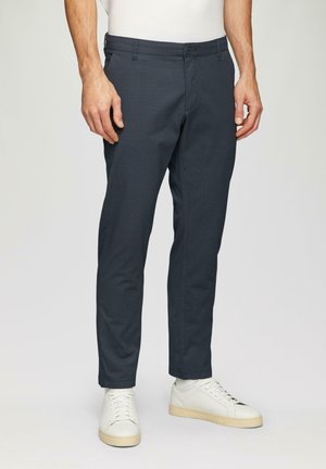 Marineblauwe slim-fit broeken van gestructureerde stof met een knoopsluiting, zijzakken en een schone zoom, gecombineerd met witte sneakers.