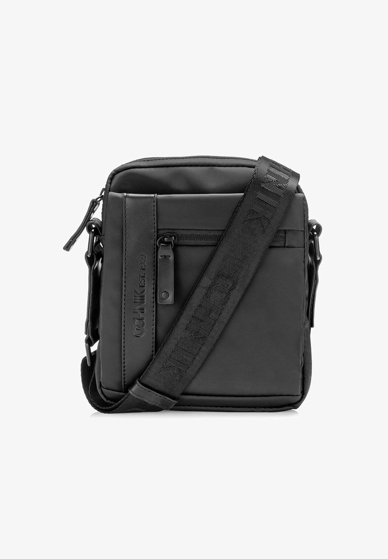 Czarna torebka na ramię wykonana z wytrzymałego materiału, z zamykaną na zamek przednią kieszenią oraz regulowanym paskiem z wytłoczonym logo. Prostokątny kształt.