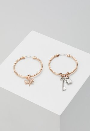 Boucles d'oreilles créoles en or rose avec un pendentif libellule sur l'une et un pendentif clé et serrure sur l'autre, toutes deux avec des accents en métal poli.