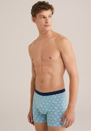 Herren-Boxershorts in Hellblau mit einem weißen Palmenmuster, ausgestattet mit einem marineblauen elastischen Bund, aus weichem, dehnbarem Material.