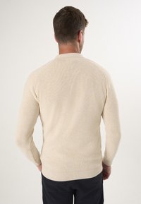 Beige geribde brei sweater met lange mouwen, ronde hals en aansluitende zoom. Soepele textuur, minimalistisch ontwerp en subtiele details bij de naden.