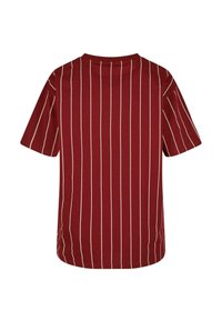 Īsām piedurknēm, bordo T-krekls ar vertikālām krēmkrāsas svītrām un noapaļotu dekoltē. Gluda auduma; ikdienišķa, brīva piegriezuma ar sānu šķēlumiem.