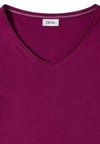 Volnočasová košile s výstřihem do V v švestkové barvě s viditelnou nášivkou značky "CECIL" přišitou na vnitřní straně výstřihu.