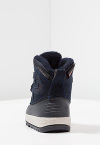 Granatowy zimowy but z teksturowaną zamszową cholewką, podszewką z polaru i wytrzymałą czarną gumową podeszwą. Posiada kontrastujące niebieskie przeszycia jako akcenty.