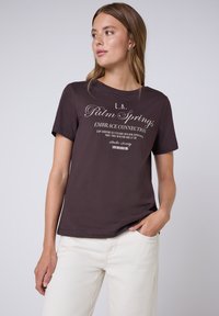 Donkerpaars katoenen T-shirt met een wit grafisch tekstontwerp. Ronde hals, korte mouwen, met een relaxte pasvorm en stikdetails aan de zoom.