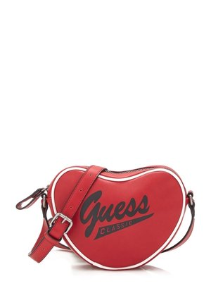 Red heart-shaped Guess Classic crossbody bag with adjustable strap and white trim on a white background.