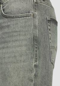 Jeans en denim gris avec une finition légèrement délavée, dotés d'une poche arrière et de matériel en métal pour plus de détails. Le tissu a une texture lisse.