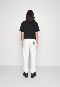 Market CALI ARC PEACE UNISEX - Calças de fato de treino - cream