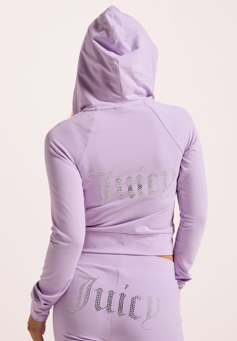 Lila, kurz geschnittenes Hoodie mit Kapuze, das auf der Rückseite mit Strassbuchstaben "Juicy" versehen ist. Hergestellt aus weichem, dehnbarem Material mit glatter Textur.
