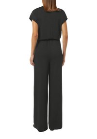 Black jumpsuit with short sleeves, elastic waistband, wide legs, and a textured fabric that adds subtle shimmer. Back view displayed.