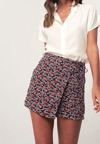 Kukkakuvioinen kietaisuhame tummansinisestä kankaasta, jossa on punaisia, valkoisia ja sinisiä kukkia. Hameessa on sivusolki ja hieman risaiset helmukset.