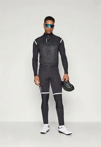 Dviračių apranga, kurią sudaro prigludęs juodas ilgomis rankovėmis marškinys su atspindinčiais akcentais, juodos kelnės su baltais juostelėmis ir šalmą. Stilingas dizainas.