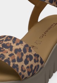 Sandale compensée avec bride à imprimé léopard marron et noir et semelle intérieure beige rembourrée avec texte du logo.