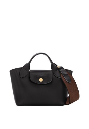 Black leather handbag with top handles, a front flap with a gold button, and a wide woven brown shoulder strap on white background.