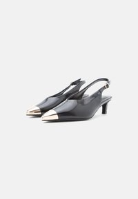 Chaussures slingback en cuir verni noir avec des bouts pointus et un capuchon doré métallique. Présente un talon modeste et une sangle réglable à la cheville.