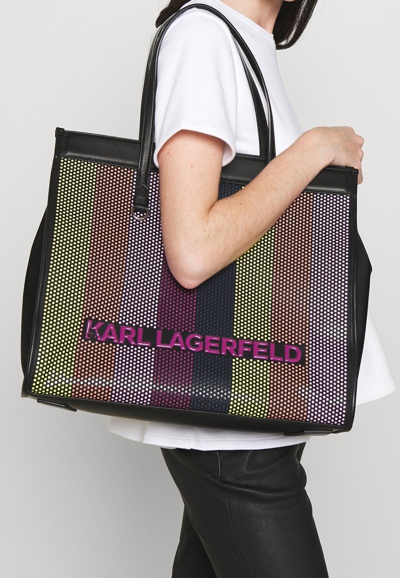 Schwarze Tragetasche mit einem mehrfarbigen Punktmuster, hellen Streifen und dem Logo "KARL LAGERFELD" in fettem Pink auf der Vorderseite.