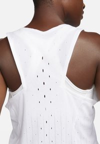 Débardeur de sport blanc sans manches, avec un dos ouvert et des perforations verticales pour la respirabilité. Tissu lisse et léger.