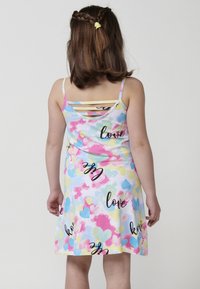 Ärmelloses Kleid aus weicher Baumwolle mit einem bunten Herzmuster in Pastellfarben. Das Rückendesign hat überkreuzte Träger; der Text lautet "Liebe."