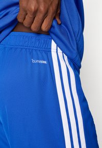 Μπλε αθλητικό σορτς από ελαφρύ ύφασμα με ζώνη μέσης και τρεις κάθετες λευκές ρίγες στο πλάι. Ορατό το λογότυπο «CLIMACOOL».