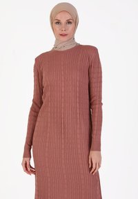 Abito lungo a coste in rosa polveroso, realizzato in tessuto testurizzato con maniche lunghe e scollatura rotonda. Accentuato da un design sobrio.