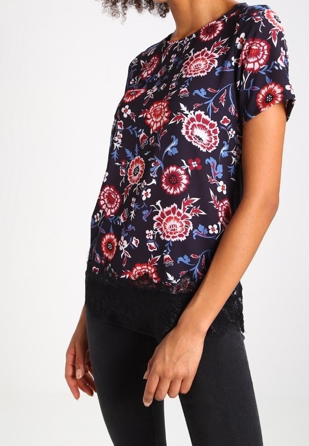 Květinová halenka tmavě námořnické modři s červenými a bílými květinovými vzory, krátké rukávy, kulatý výstřih a černá krajková lemovka.