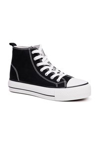 Zwarte high-top sneakers van canvas, met witte veters, een rubberen teenkap en een dikke witte zool met een zwarte stripe.