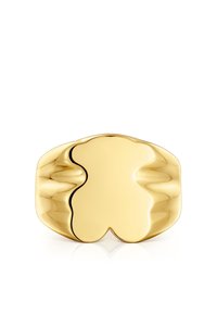 Anello in metallo dorato con una superficie liscia e riflettente, caratterizzato da un design astratto e ondulato. I bordi curvi creano una forma organica.