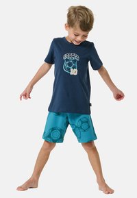 Navy t-shirt met een voetbalgrafiek en het detail "10", gecombineerd met turquoise shorts met een patroon van voetballen. Zacht katoenmateriaal.