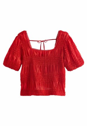 Röd, smockad blus med fyrkantig halsringning, korta puffärmar och stängning med snörning bak. Har textil med strukturerad yta och horisontella rynkor.