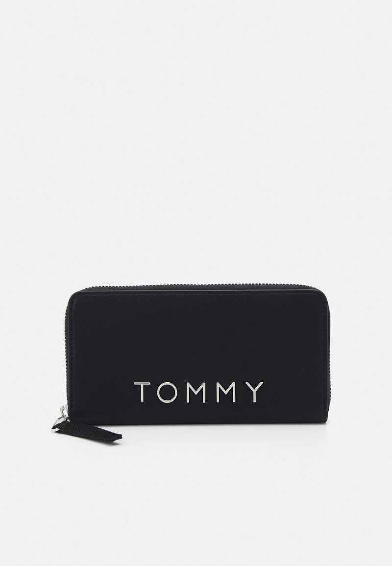 Černá peněženka na zip vyrobená z hladké látky, na přední straně s metalickým stříbrným logem "TOMMY" a s texturovaným táhlem na zip.