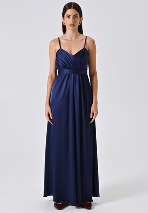Robe maxi satin bleu marine avec fines bretelles, corsage plissé et taille cintrée. Texture lisse avec une silhouette fluide.