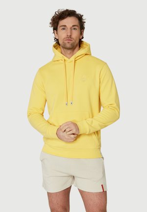 Gul sweatshirt med huva, tillverkad av mjukt material, med en framfick och snoddar, samt en diskret avokadologga på bröstet.