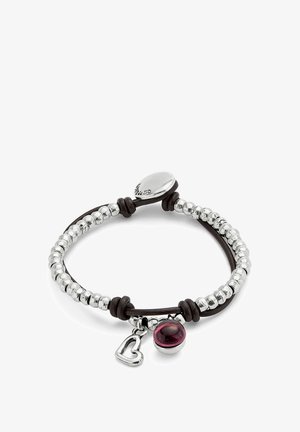 Pulsera de cuentas de plata con cordón de cuero marrón, que presenta una piedra marrón y un charm de corazón. Cierre circular con detalles grabados.