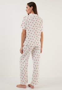 Set pijama kratkih rukava svijetlosive boje s uzorkom crvenih trešanja, s dugmadi na revere i hlačama opuštenog kroja, izrađeno od mekanog pamučnog materijala.