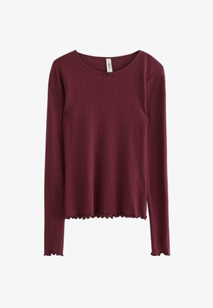 Burgundy pitkähihainen paita ribbikankaasta, jossa on pyöreä kaula-aukko ja aaltoileva helma. Kankaan pinta näyttää pehmeältä ja hieman joustavalta.