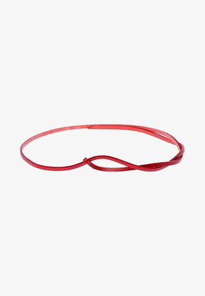 Ceinture fine en cuir rouge tordue en une boucle lâche sur fond blanc.