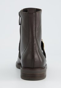 Botte de cheville en cuir brun avec une pointe arrondie, fermeture éclair sur le côté et tirette à l'arrière ; elle présente une semelle accentuée en bois et un minimum de coutures.