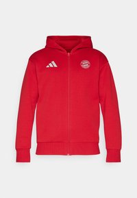Felpa rossa con zip presenta una tasca frontale, polsini e orlo a costine. Mostra il logo bianco di Adidas e l'emblema del Bayern Monaco sul petto.
