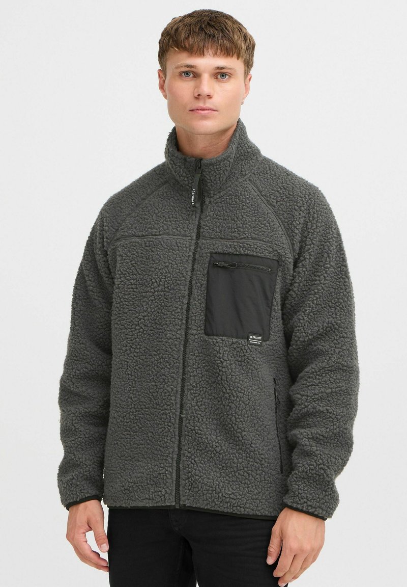 Graue Fleecejacke mit hohem Kragen, Reißverschluss-Brusttasche und schwarzen Akzenten. Verfügt über einen strukturierten Stoff und eine lockere Passform.