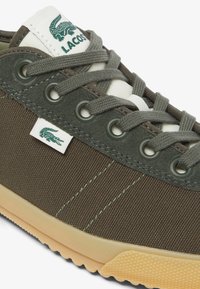 Sneaker verde in tessuto con finitura testurizzata, dotata di occhielli rotondi, suola beige e linguetta bianca con logo verde Lacoste.