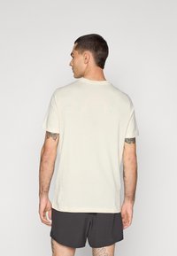 Svet t-skjorte i off-white, med rund hals og korte ermer, i en avslappet passform. Minimalistisk design, glatt tekstur.