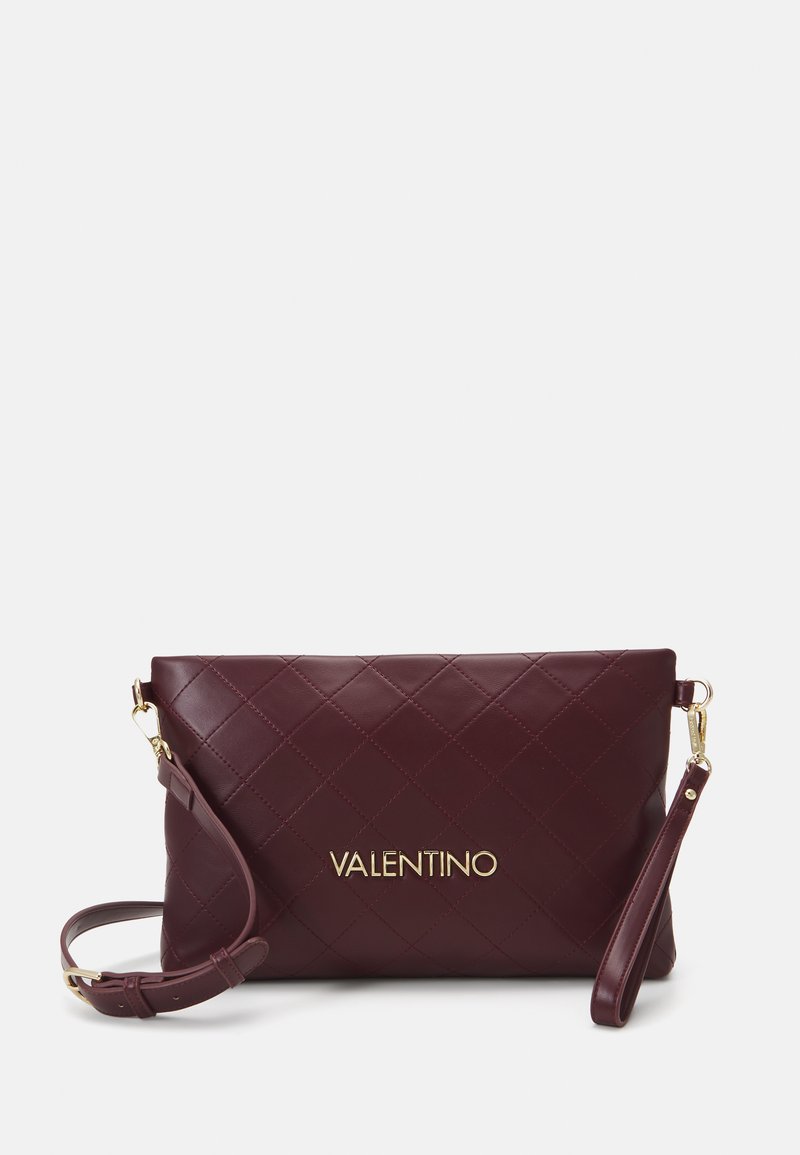 Quiltana temno burgundska Valentino torbica s zlatim logotipom, snemljivo zapestnico in nastavljivim ramenskim trakom na enobarvni ozadju.