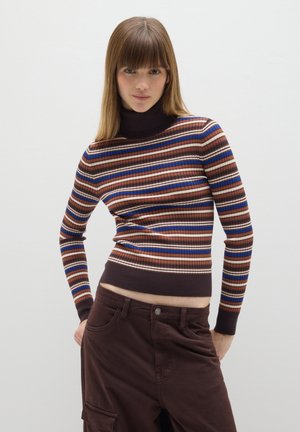 Maglione a collo alto a righe nei toni del marrone, ruggine e blu, con texture a costine; design croppato, silhouette aderente, abbinato a pantaloni marroni.