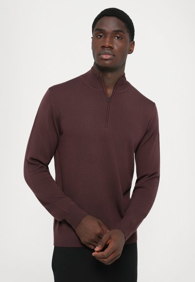 Pullover bourgogne avec un col montant et une demi-fermeture éclair. Texture côtelée et manches ajustées. Fabriqué en tissu tricoté.